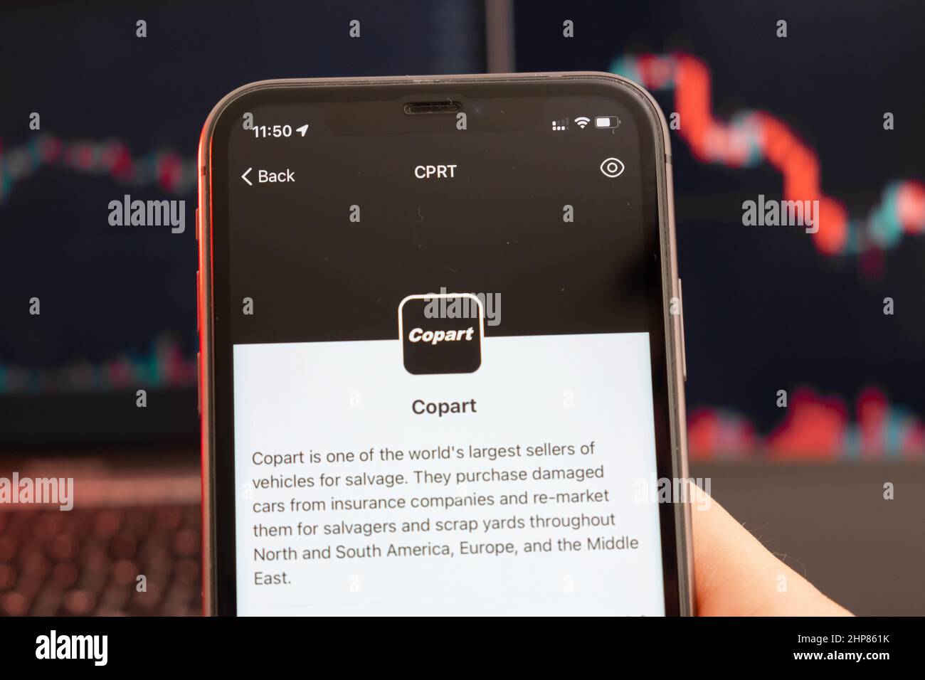 Copart stock price decrease on the trading market with downtrend line graph bar chart on the background. Man holding a mobile phone with company logo, February 2022, San Francisco, USA.  Stock Photo