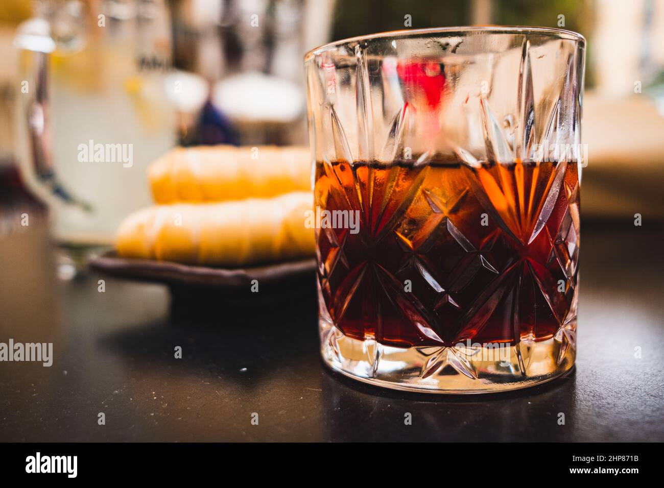 glass of dark vermouth drink with slice of orange on a bar table outdoors, a popular aperitif