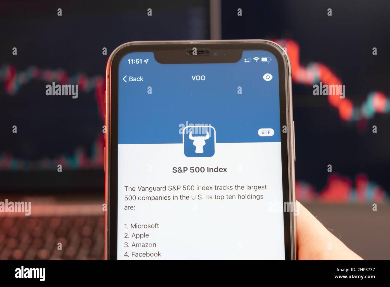 SP 500 Index stock price decrease on the trading market with downtrend line graph bar chart on the background. Man holding a mobile phone with company logo, February 2022, San Francisco, USA.  Stock Photo