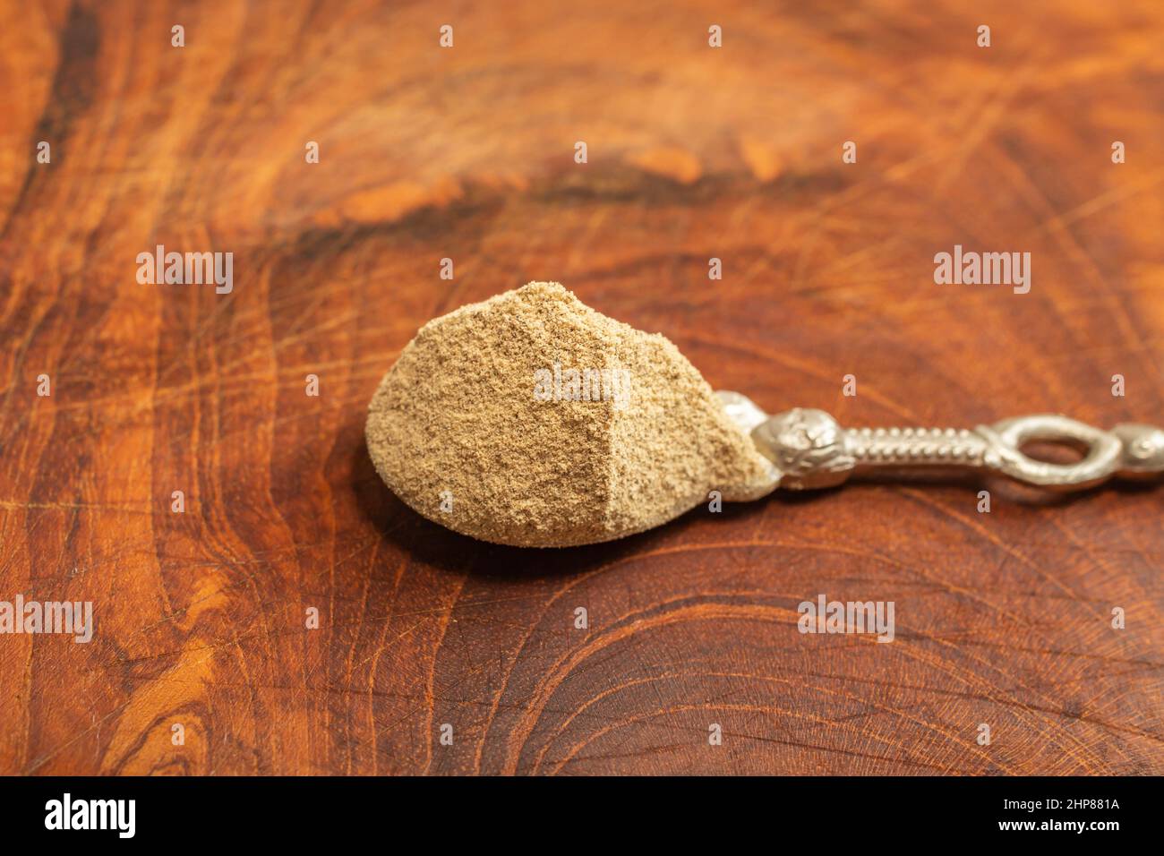 silver teaspoon full of grounded white pepper , on a wooden chopper Stock Photo
