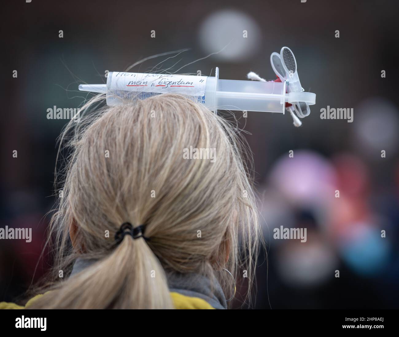 19 February 2022, Hessen, Frankfurt/Main: A woman carries a syringe on her head with the inscription "My body, my property" during a demonstration of several thousand people against corona measures and compulsory vaccination in downtown Frankfurt. Photo: Frank Rumpenhorst/dpa Stock Photo