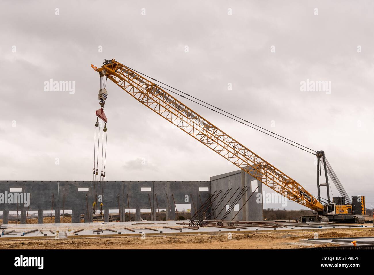 Large yellow mobile crane at construction site and used to lift large sections of prefabricated building walls into place Stock Photo