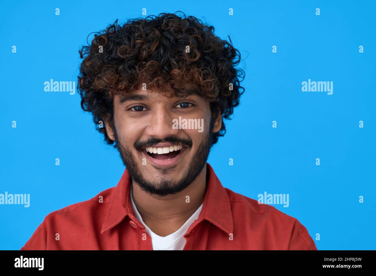 Happy young indian guy laughing isolated on blue background. Headshot portrait Stock Photo