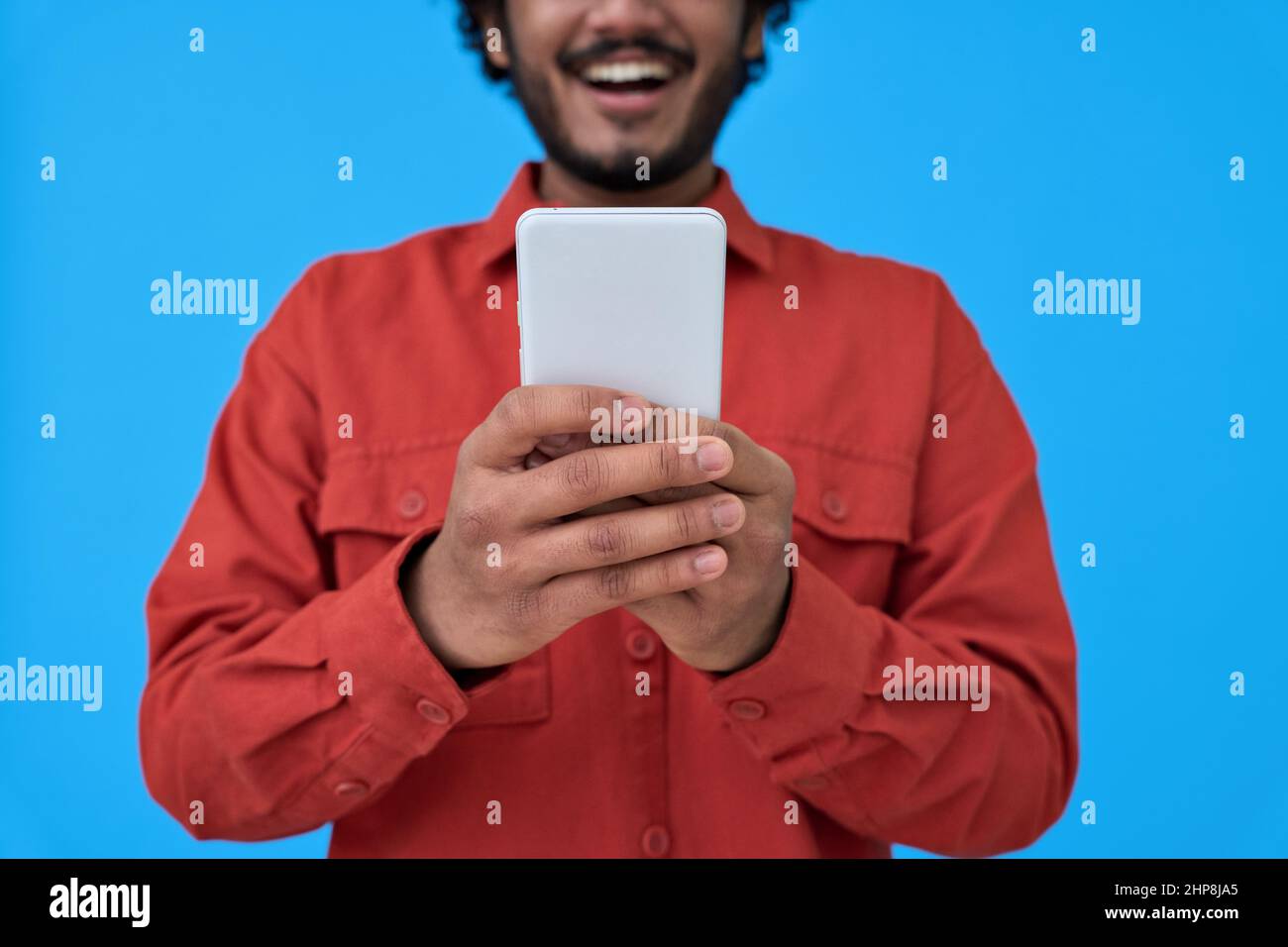 Happy young man using cell phone isolated on blue background. closeup Stock Photo