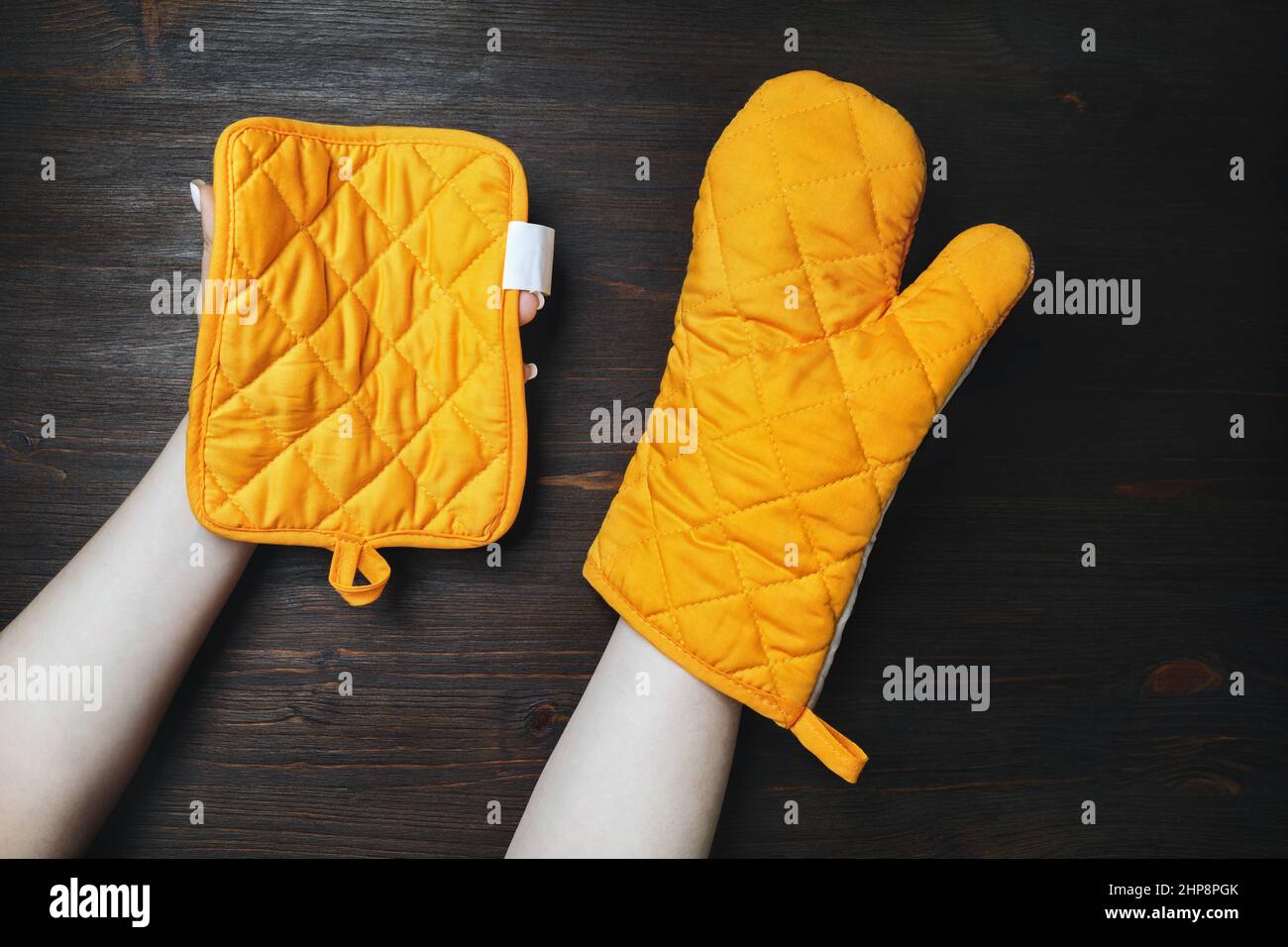 Yellow cooking mitten and potholder for hot dishes in female hands