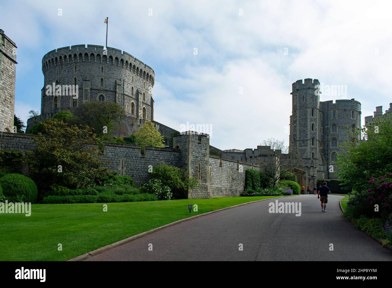 A male visitor on Castle Hill Road towards the entrance of Windsor Castle. The Round Tower and Edward III Tower stand over the castle walls. Stock Photo