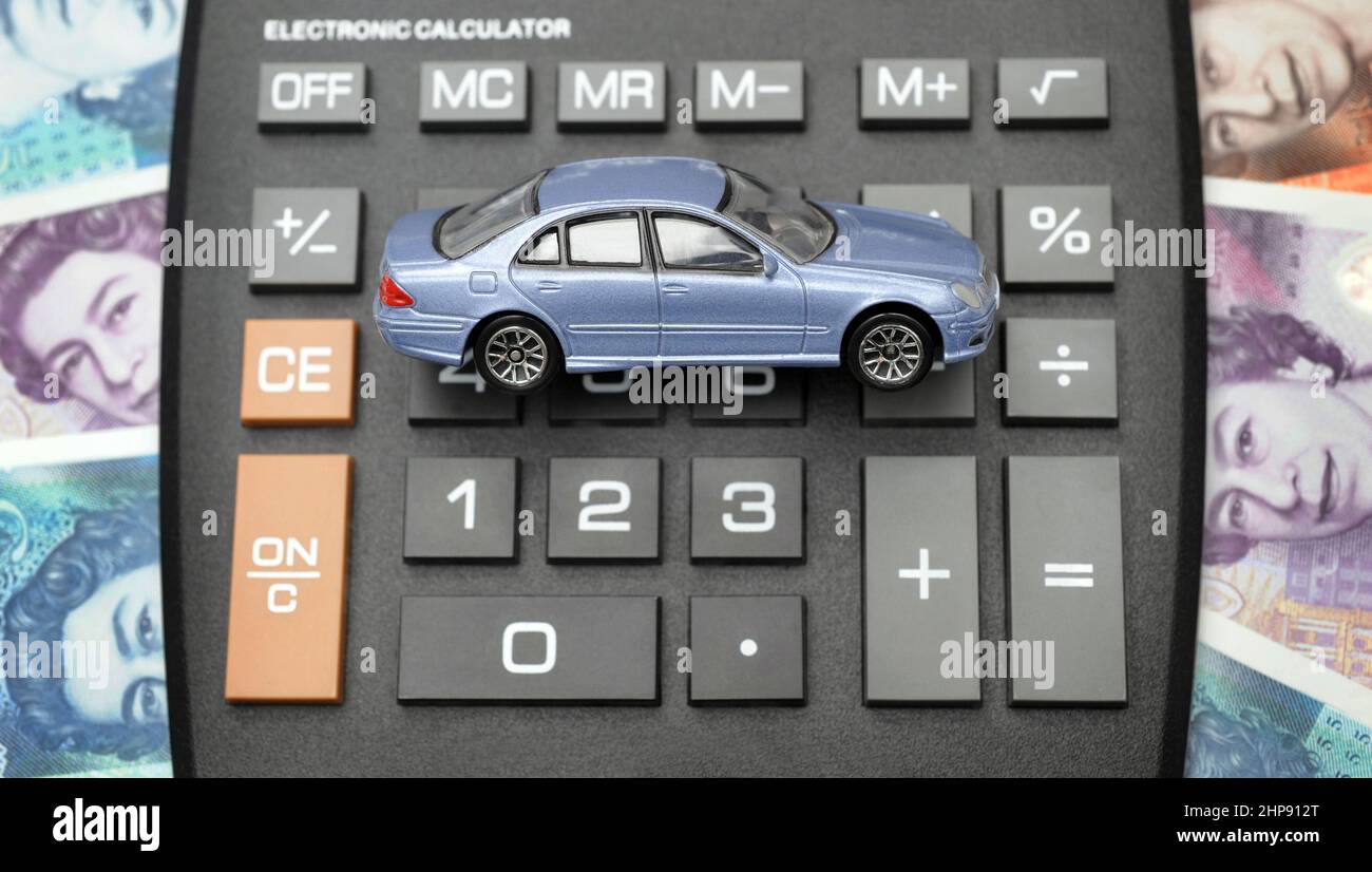 MODEL CAR ON CALCULATOR WITH MONEY RE INSURANCE COSTS BUYING REPAIRS TAX EMISSIONS ETC UK Stock Photo