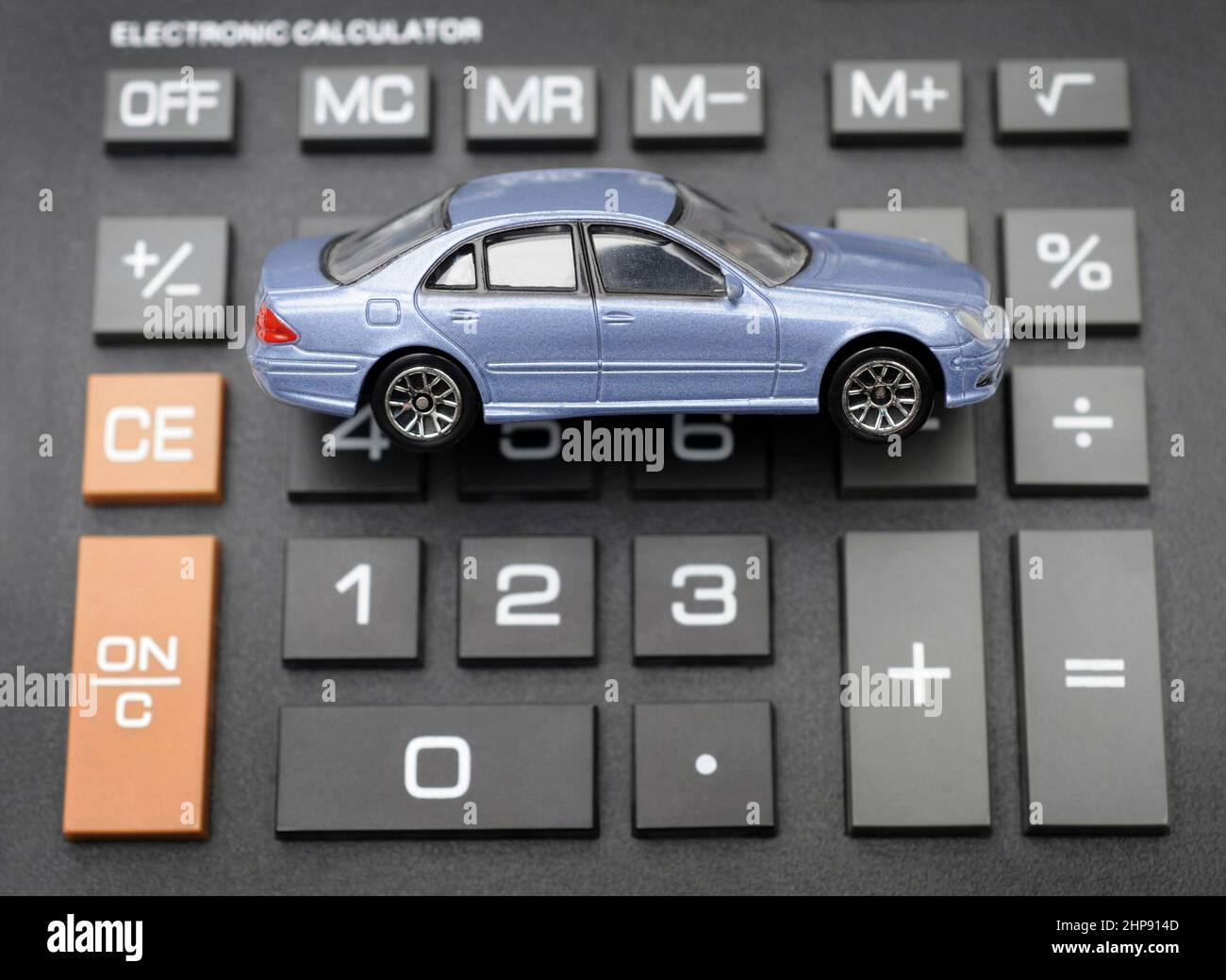 MODEL CAR ON CALCULATOR RE INSURANCE COSTS BUYING REPAIRS TAX EMISSIONS ETC UK Stock Photo