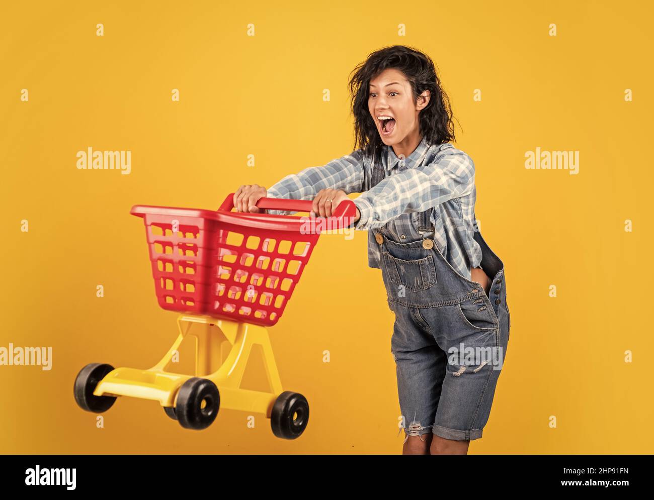 surprised woman carry shopping cart. girl in checkered shirt and jeans