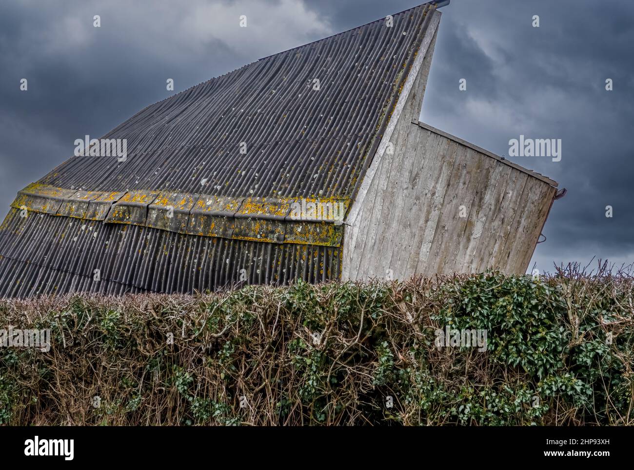 wooden horse stables blown over on to its side strong winds of a storm, thunder storm dark cloud sky Stock Photo