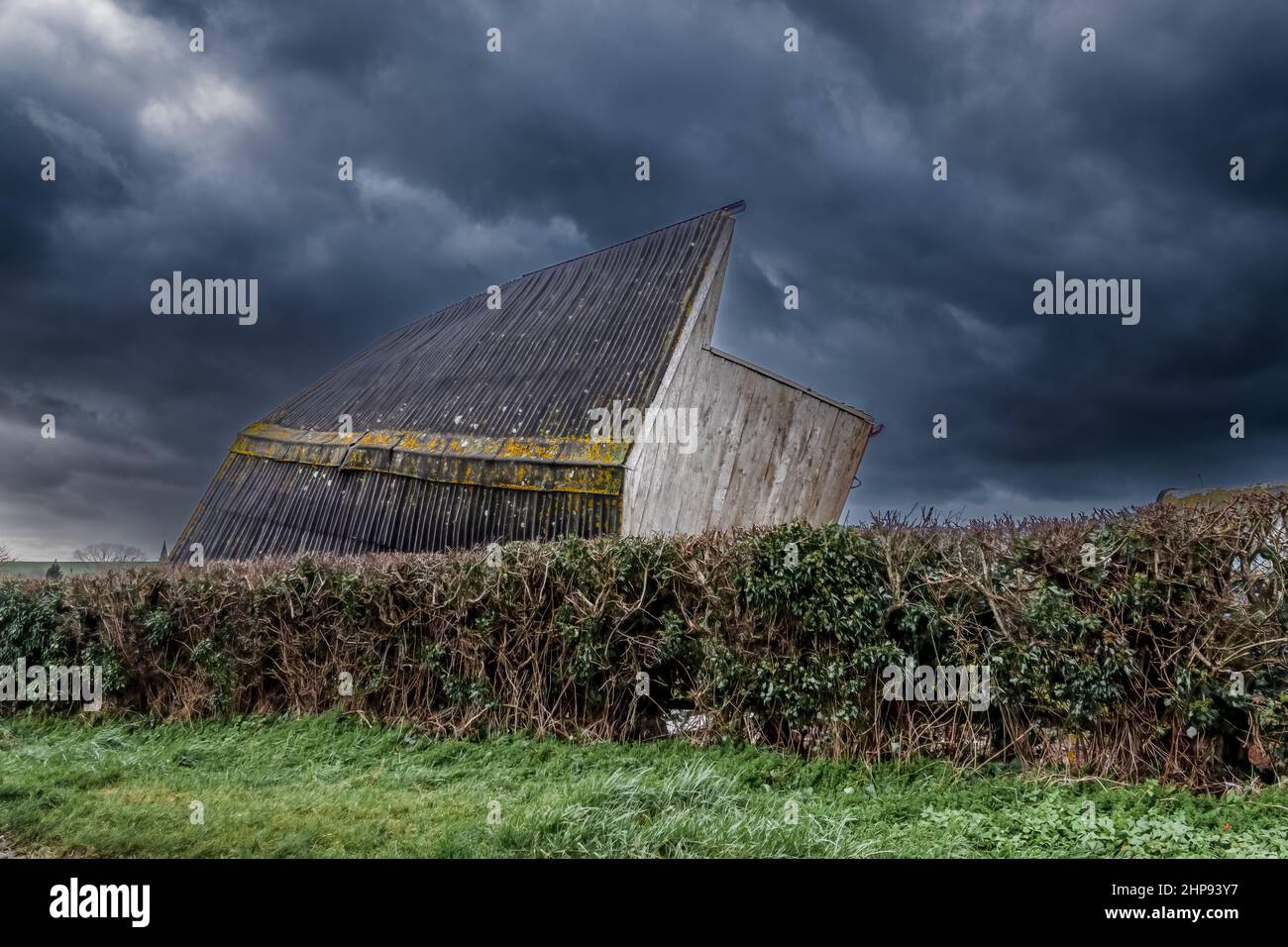 wooden horse stables blown over on to its side strong winds of a storm, thunder storm dark cloud sky Stock Photo