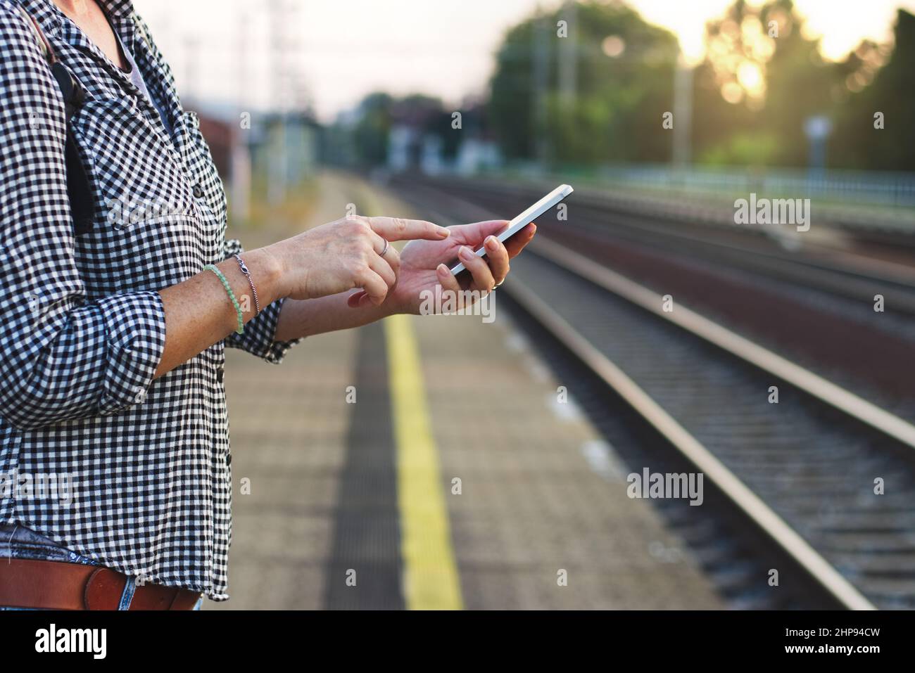 Woman using smart phone on railway station. Travelling in Europe by train. Stock Photo
