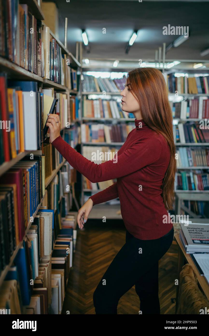 A girl holding a book shelf, student in the library Stock Photo - Alamy