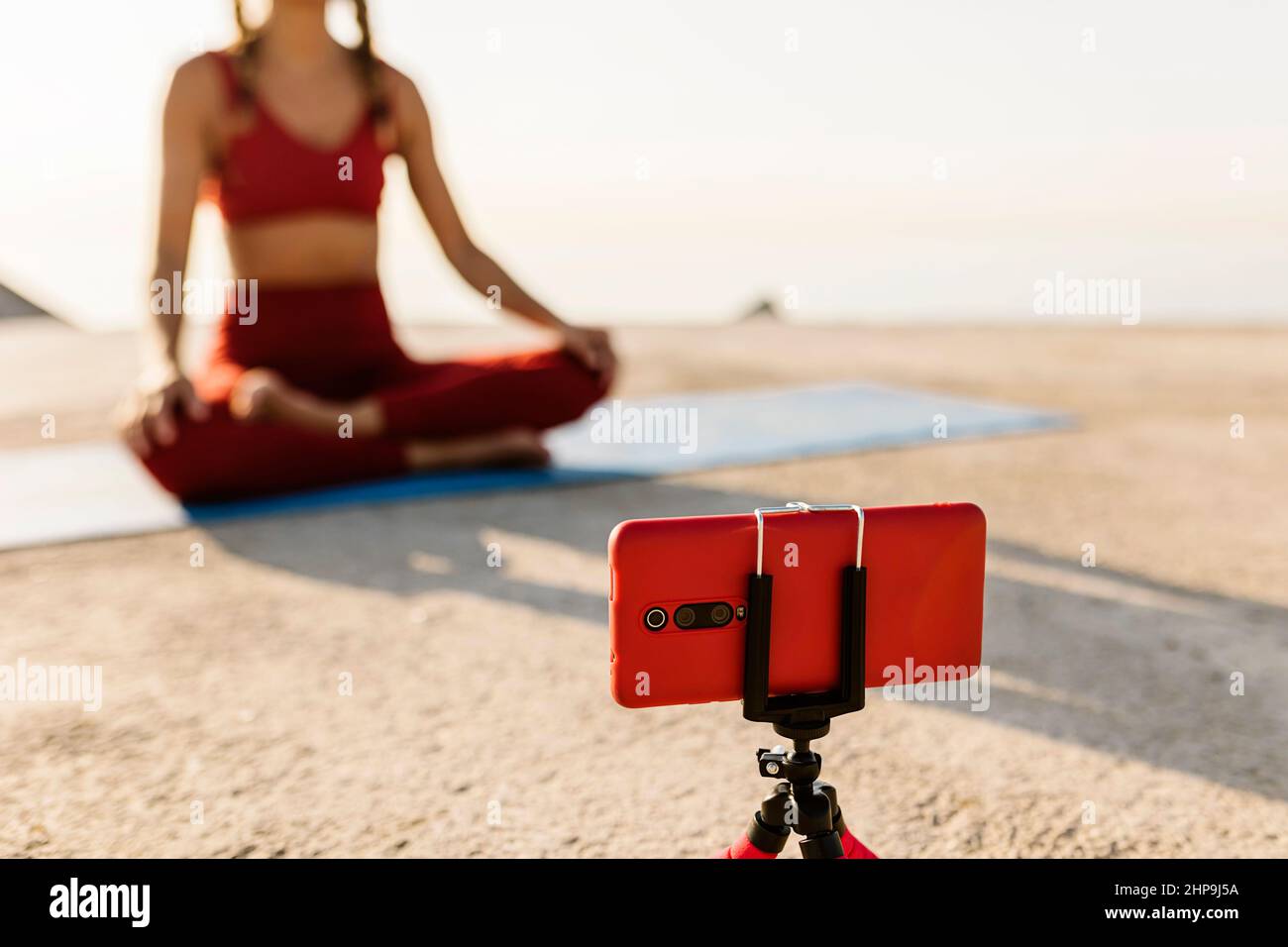 Female instructor teaching online yoga lessons through video call on phone Stock Photo
