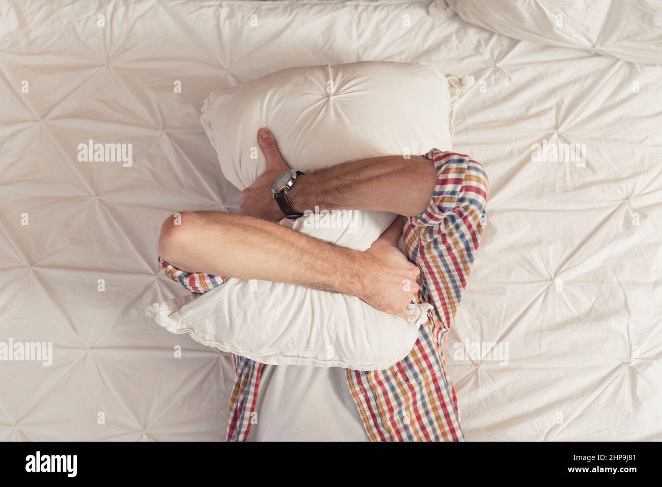 lonely jobless caucasian man hugging his pillow and covering his tears. High quality photo Stock Photo