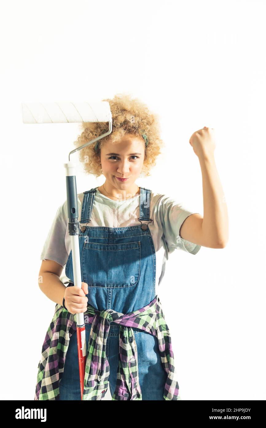 Confident strong mixed race woman with roller and dungarees - isolated white background. High quality photo Stock Photo