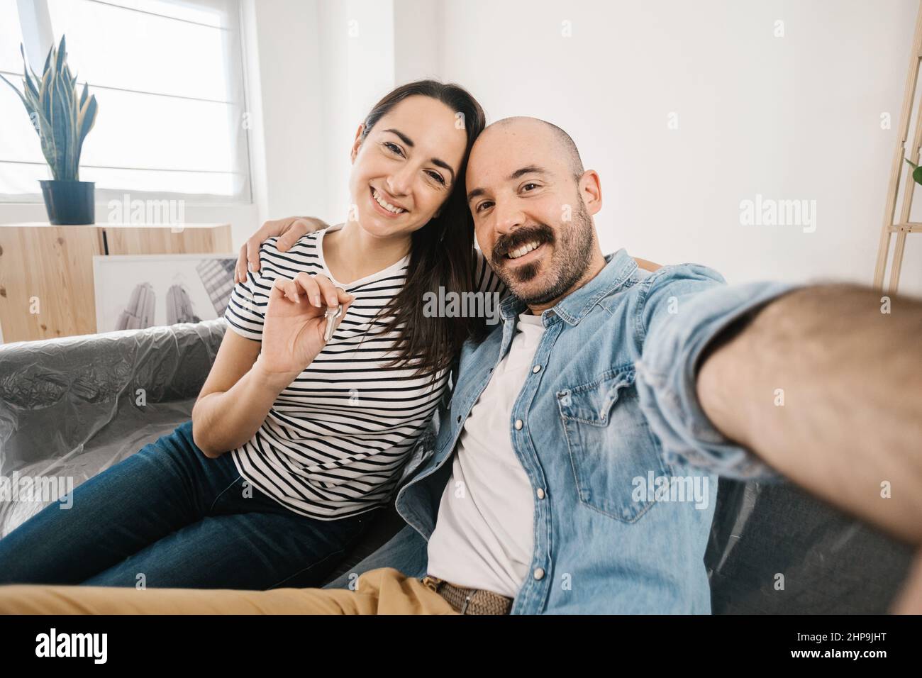 Happy young adult couple taking selfie photo after moving to new apartment Stock Photo
