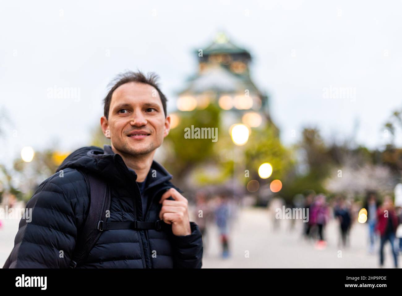 Osaka, Japan castle in evening with happy man tourist caucasian person happy smiling standing by building at night bokeh background with illumination Stock Photo