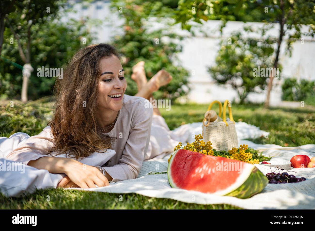 Portrait of beautiful woman posing lying on plaid at summer garden park ...