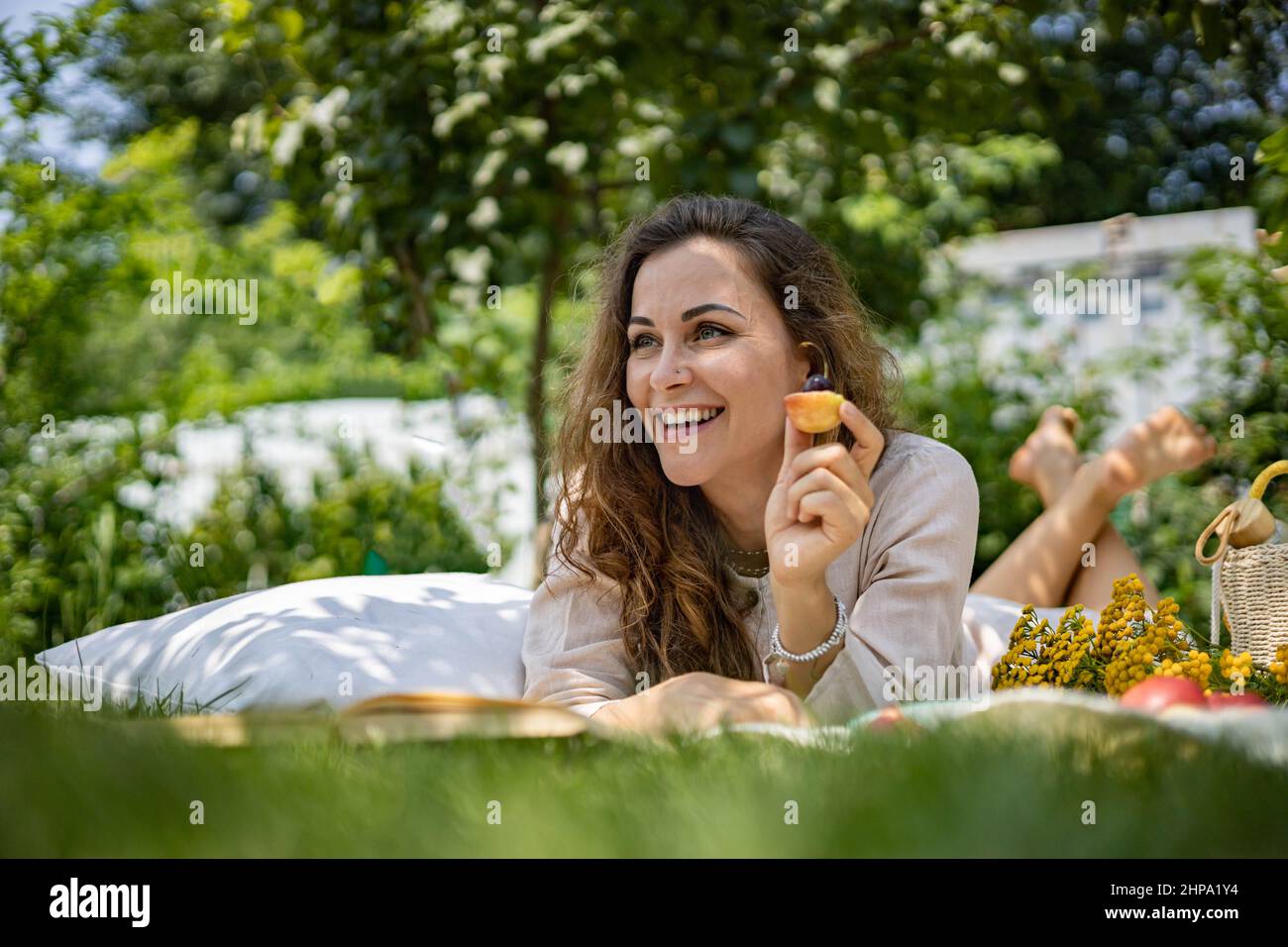 Portrait of beautiful woman posing lying on plaid at summer garden park ...