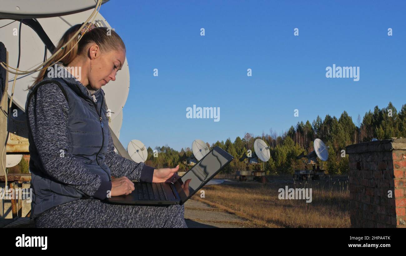 Woman student operator of institute of Solar Terrestrial Physics monitors communication equipment in notebook. Unique array solar radio telescope. Sun Stock Photo