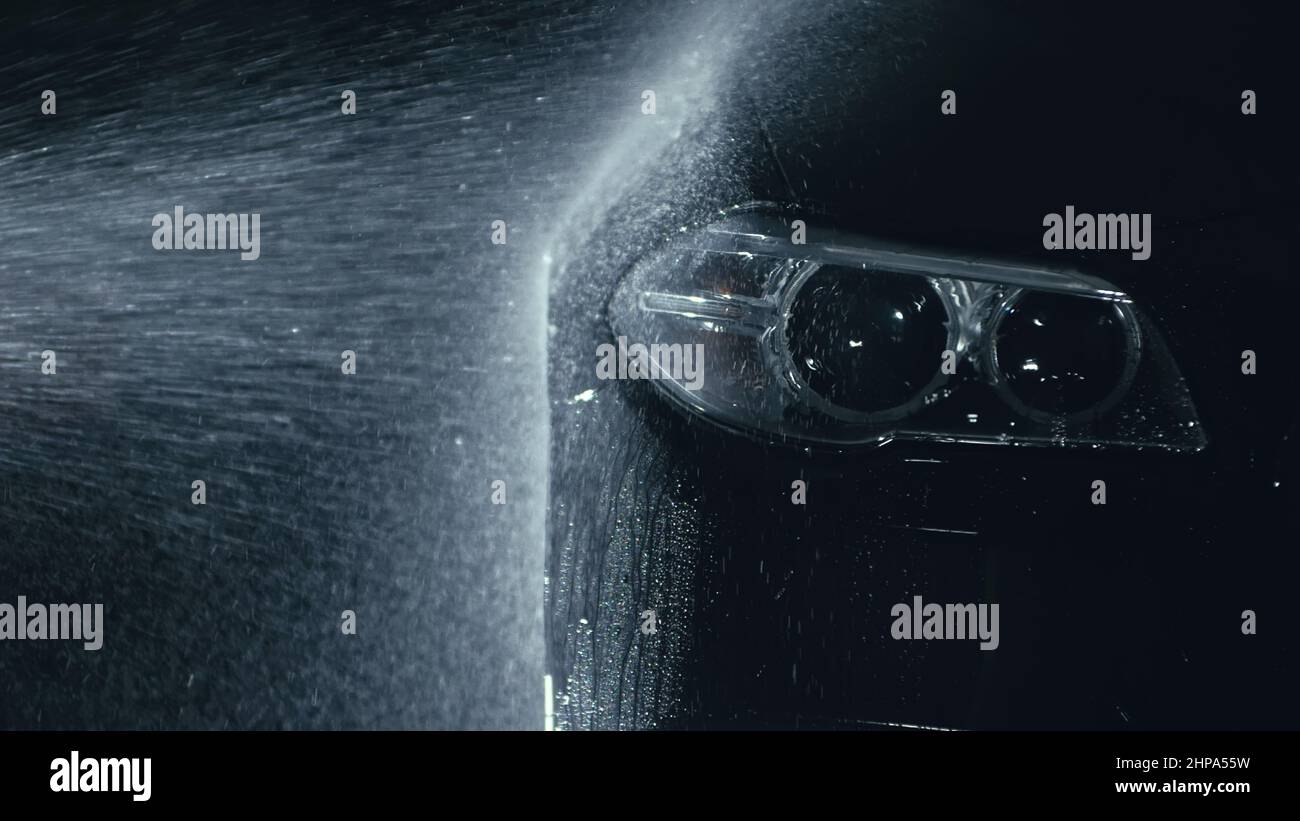 Car headlight wash. Washing modern vehicle body by high pressure jet
