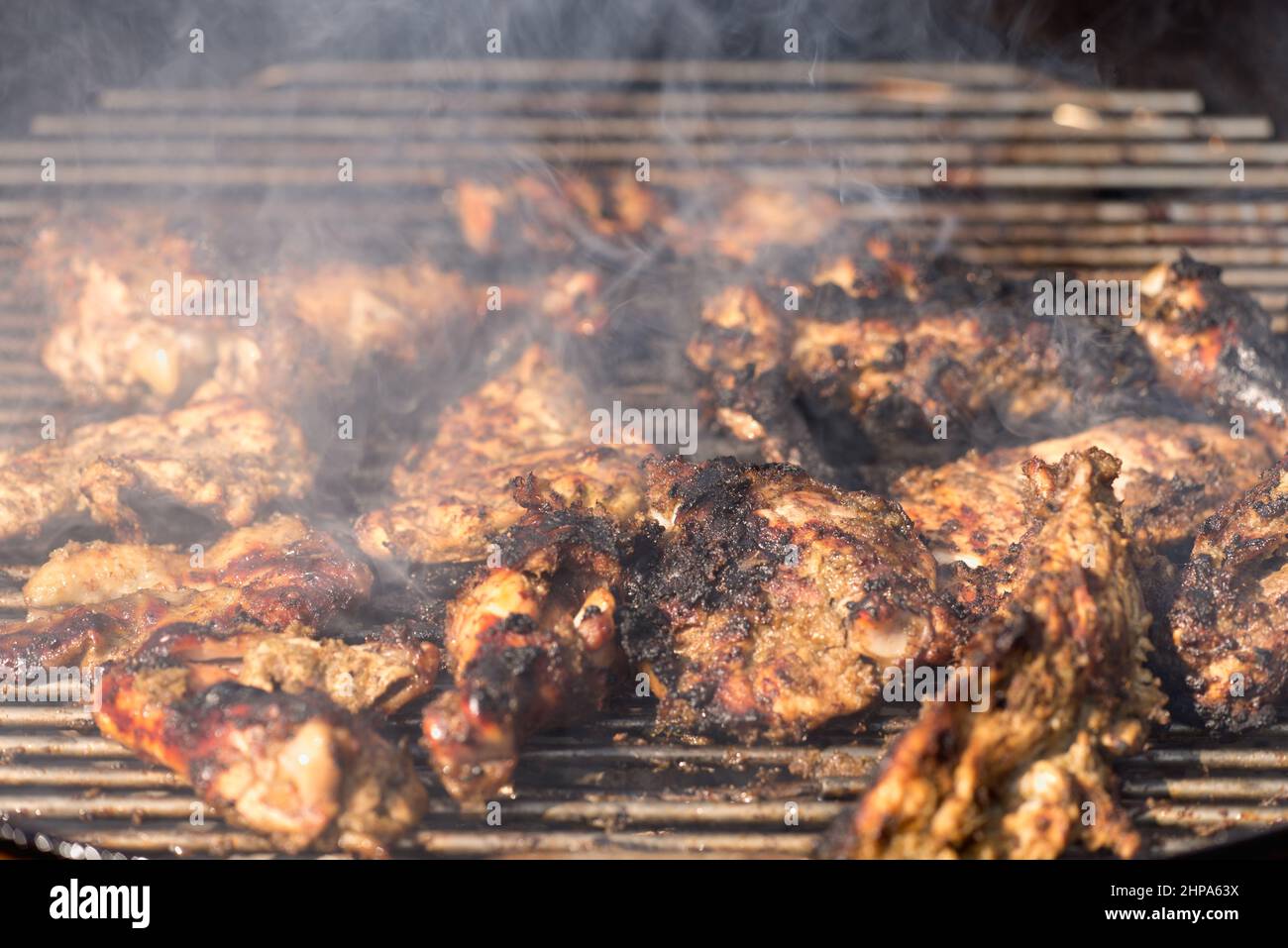 Grilling traditional Jamaican spicy jerk chicken with over wood fire