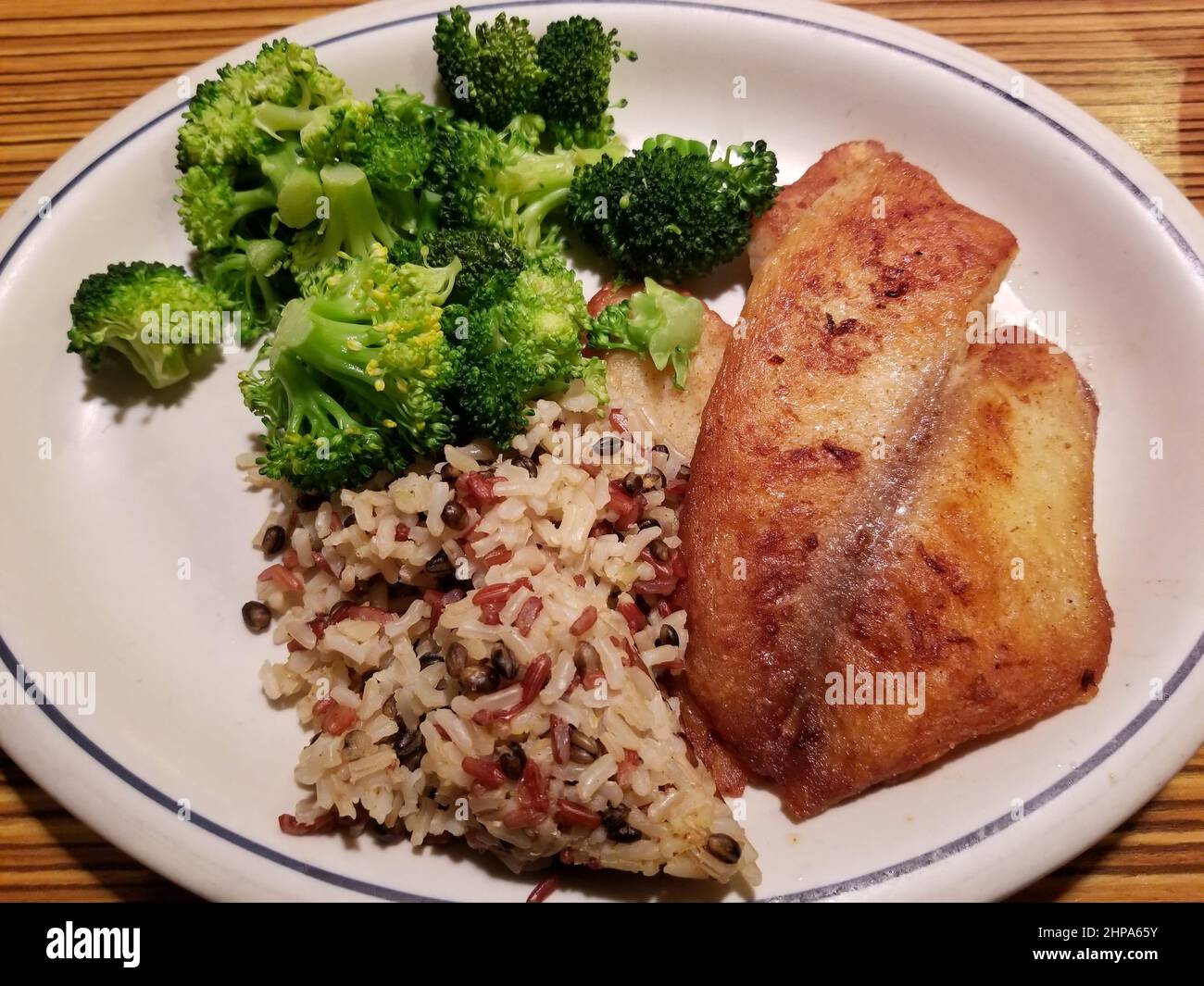 Fried tilapia served with red rice and broccoli Stock Photo Alamy