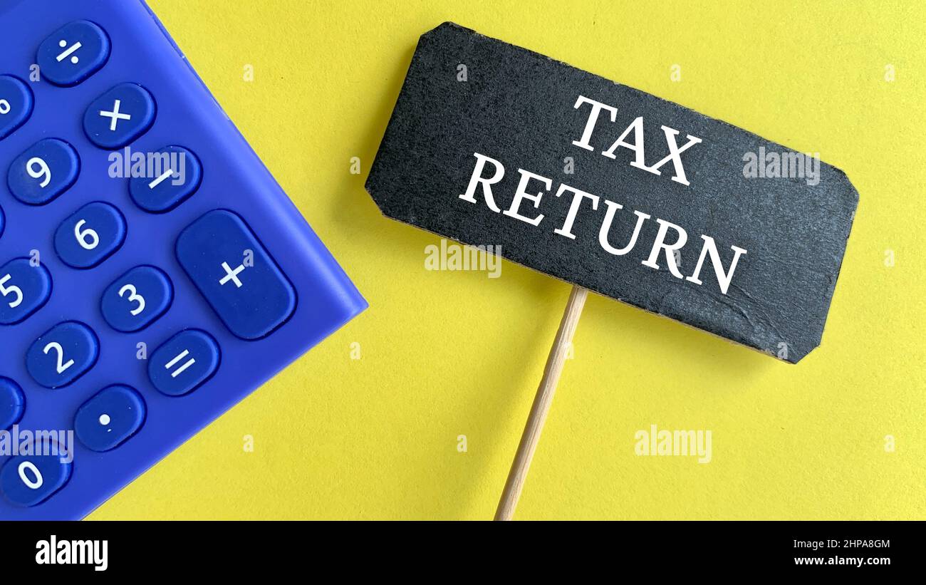 Top view of calculator and a black tag with TAX RETURN word on yellow