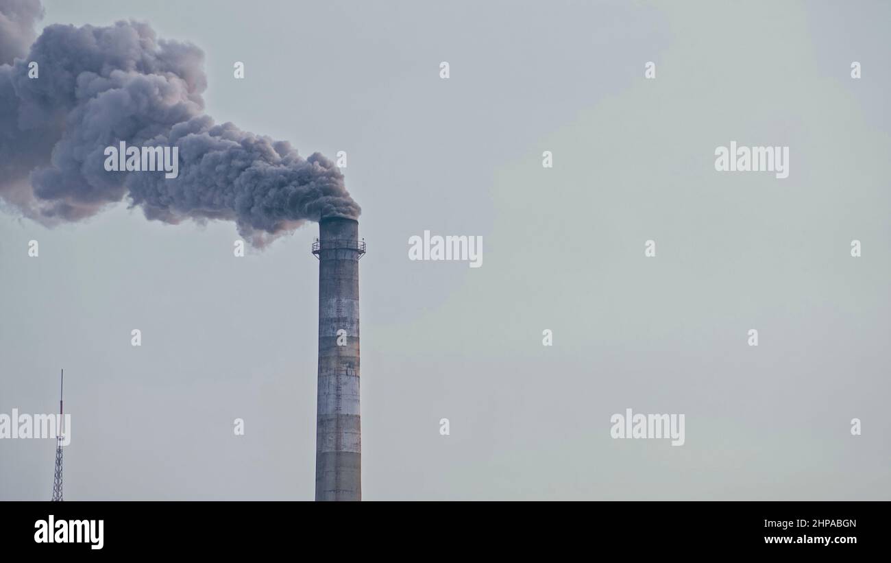 This smoke coming from the chimney in a factory. Harmful emissions into the atmosphere, from the pipe. Serious damage the environment. Plant stack Coaling station. Close up shot. Dark sad view. Stock Photo