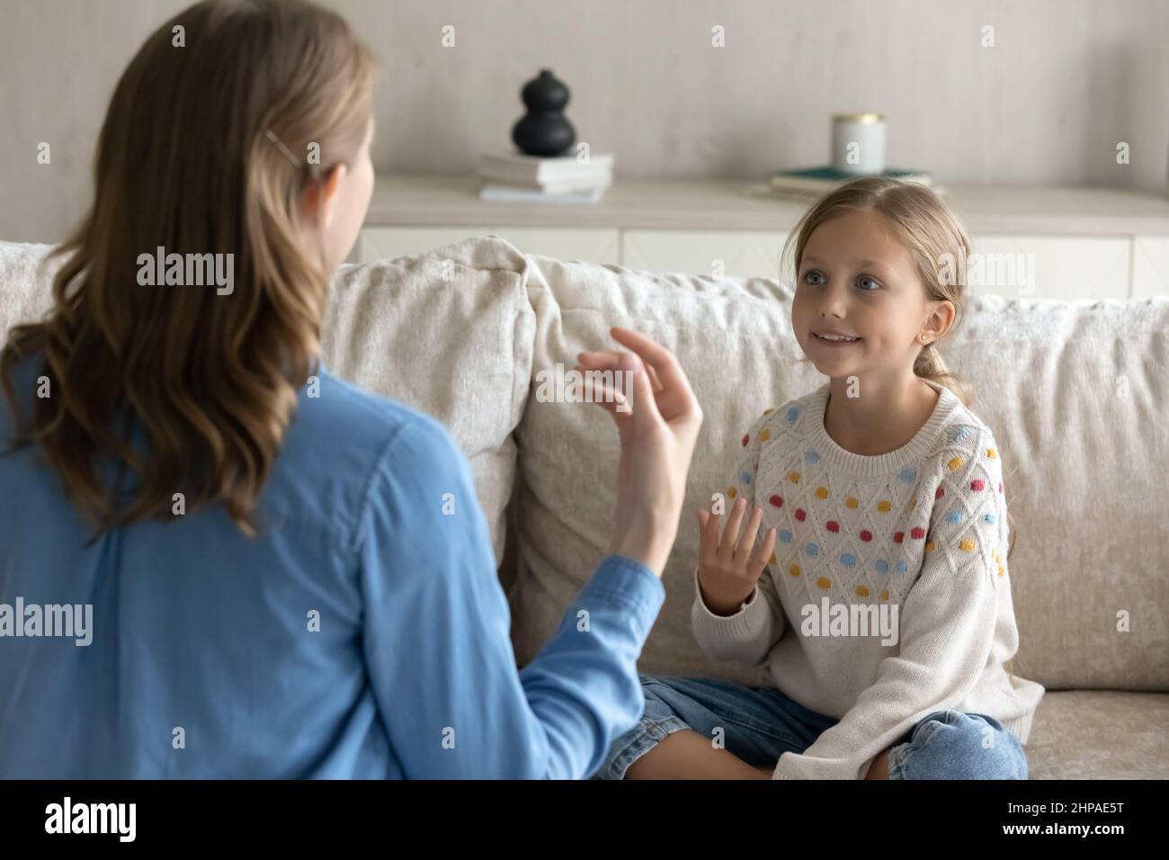 Female therapist teaching pretty kid girl to speak gestures language Stock Photo