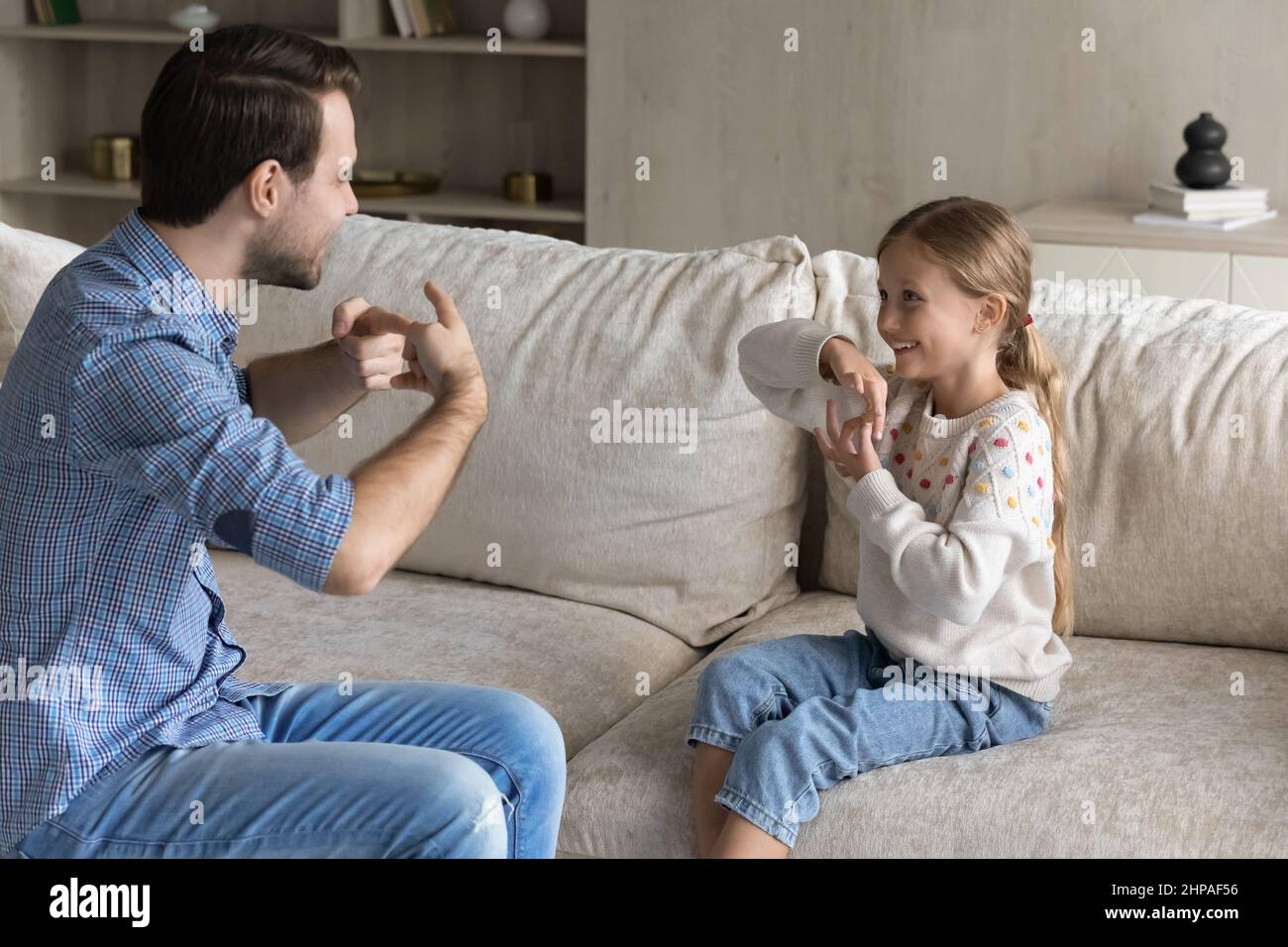 Cheerful excited dad and daughter girl with hearing disorder talking Stock Photo