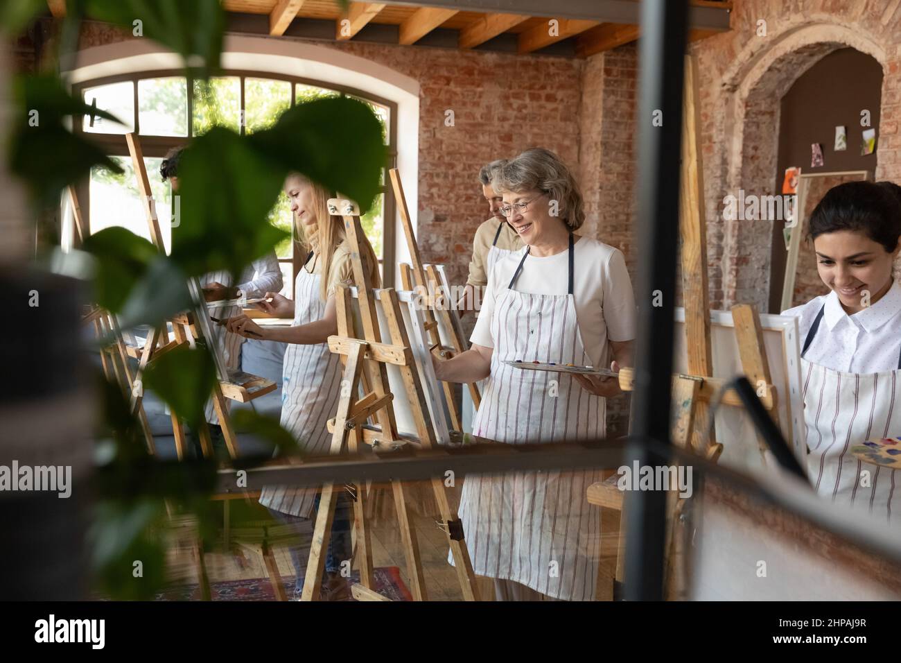 Happy old woman enjoying creative art group lesson. Stock Photo