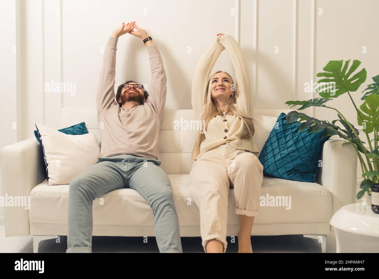 Calm lazy caucasian couple relaxing together on comfortable sofa and stretching their arms in the air. High quality photo Stock Photo