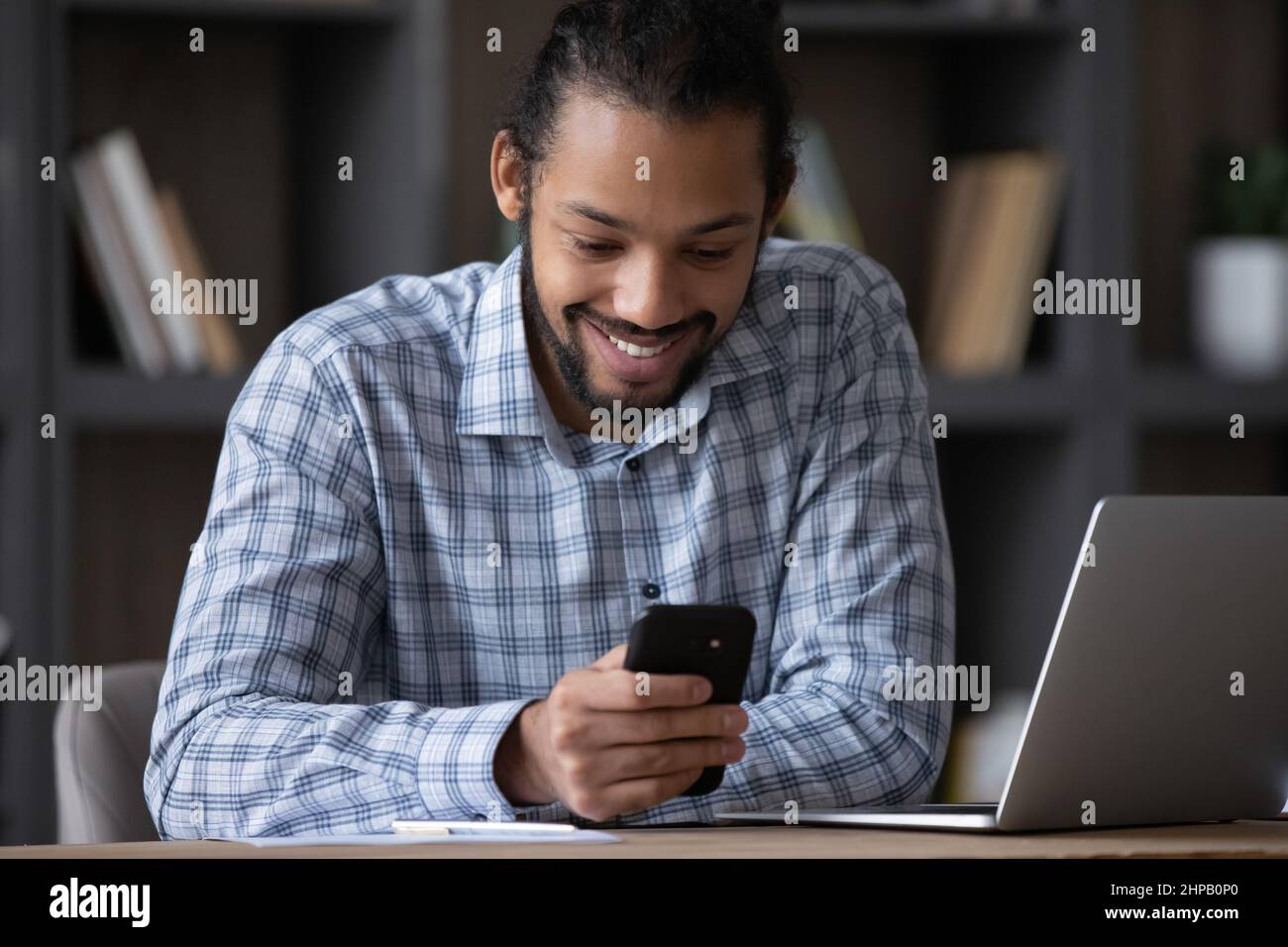 Happy handsome young African American man using mobile apps. Stock Photo