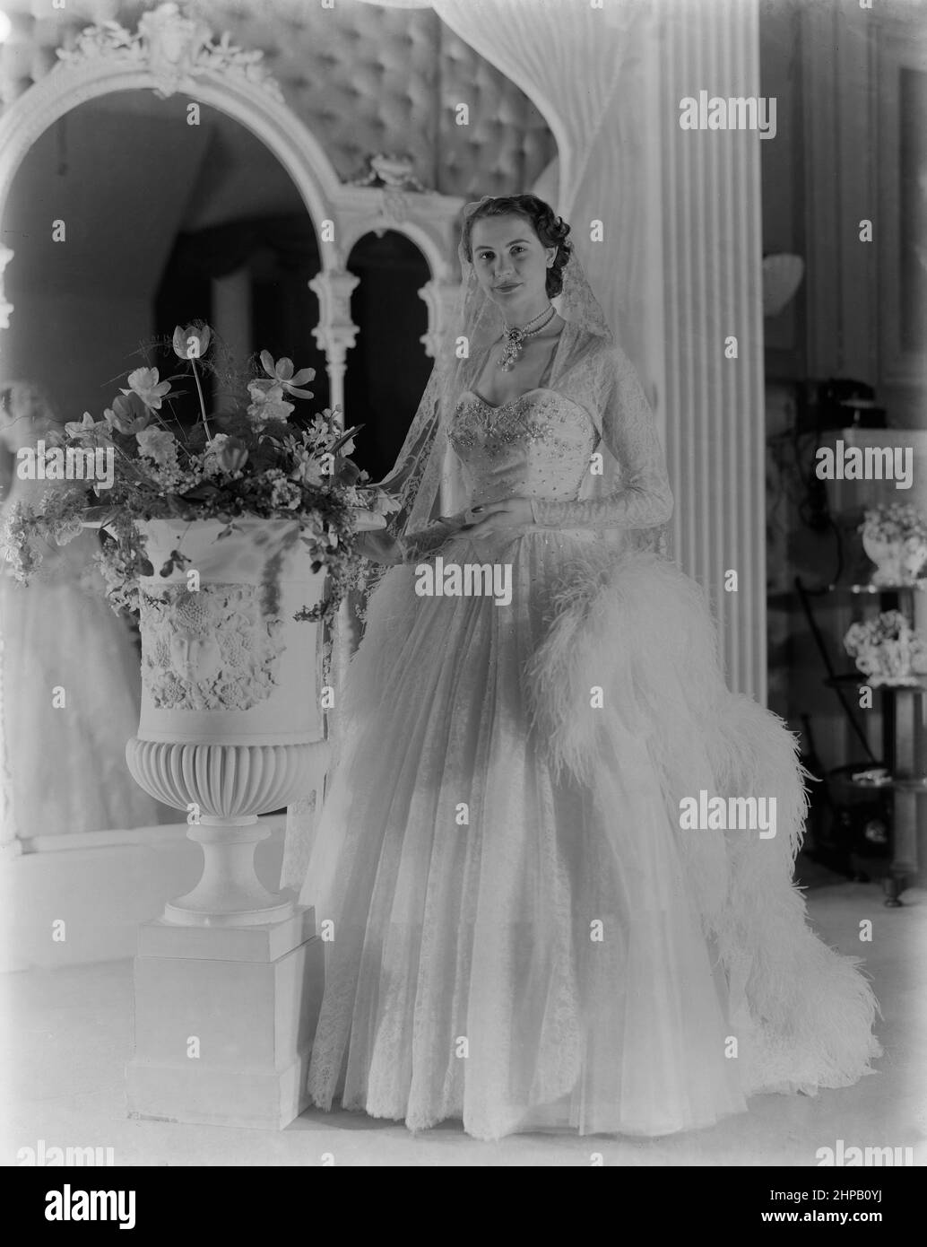 A British fashion model, from a professional photoshoot from the 1950s. Modelling a very elaborate gown. Stock Photo