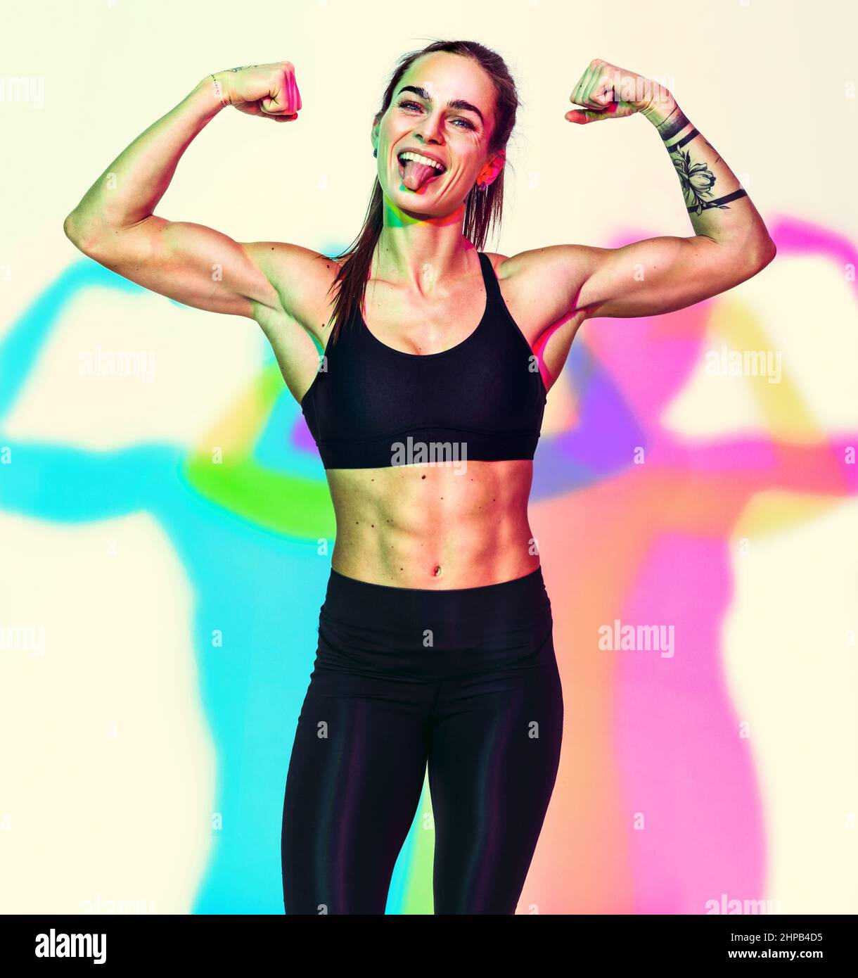 Strong woman after workout showing her muscles. Photo of woman with perfect physique on white background with effect of rgb colors shadows. Strength a Stock Photo