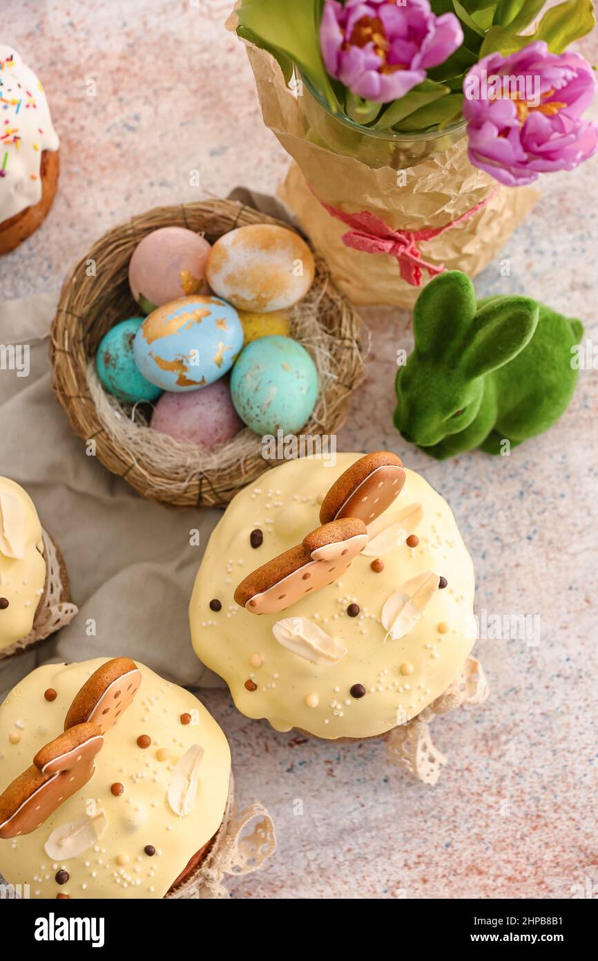 Tasty Easter cakes and nest with eggs on light background Stock Photo
