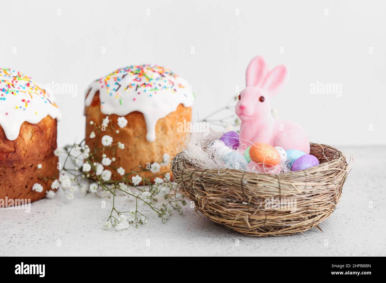 Nest with Easter bunny, eggs and cakes on table Stock Photo
