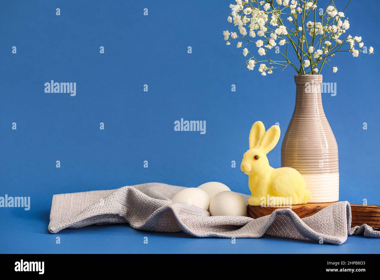Cute Easter bunny, eggs and vase with gypsophila flowers on color ...