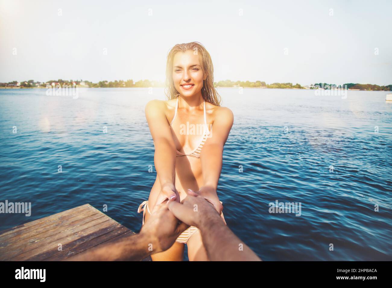 Woman in swimsuit takes by the hand her boyfriend in the sea Stock Photo