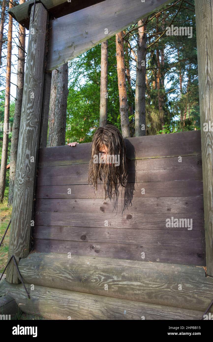 the head of a girl with long disheveled hair clamped in a guillotine, a scene of a medieval execution, a sentence. Stock Photo