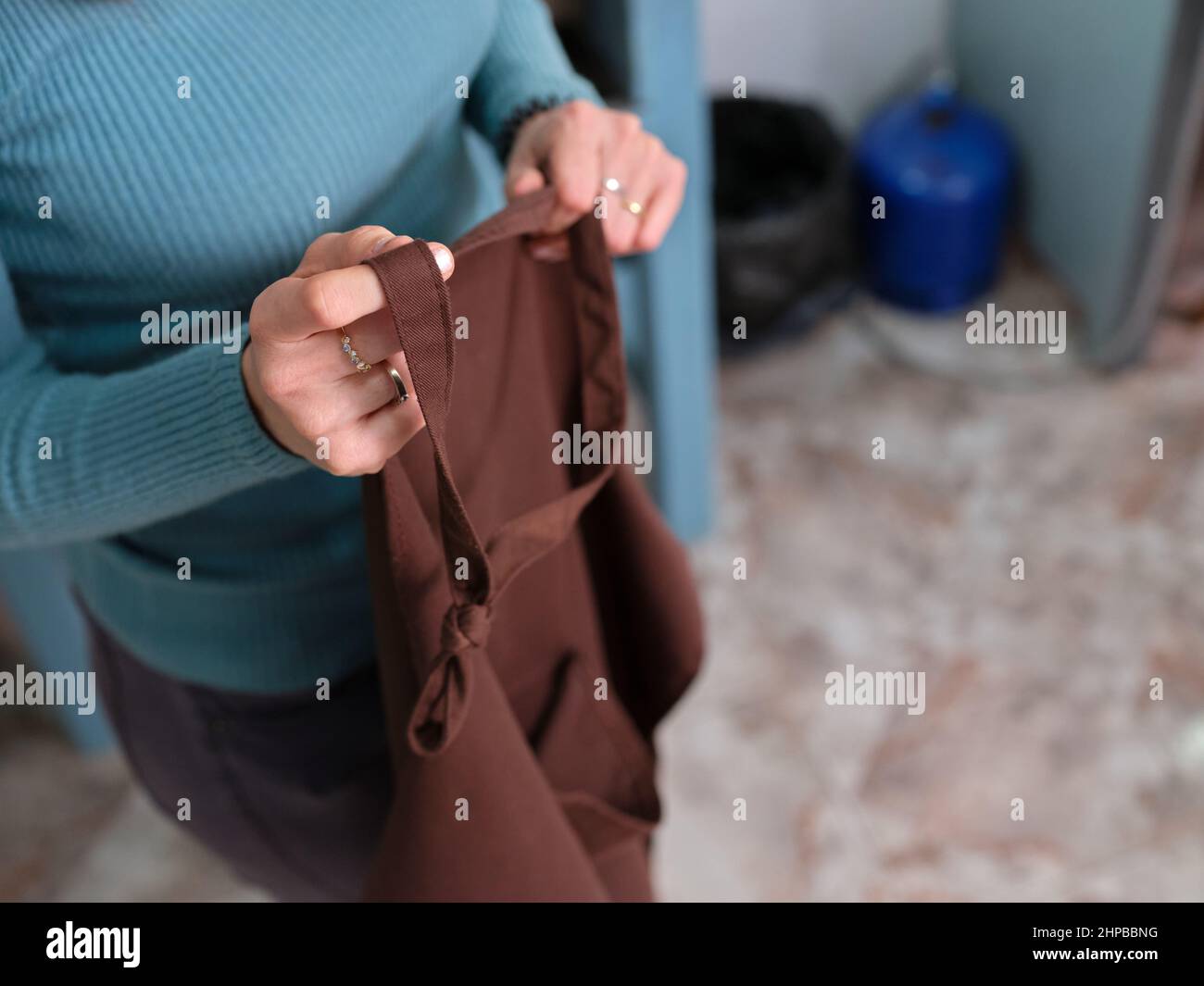 an unrecognizable adult worker woman holding her work apron in her handicraft workshop Stock Photo