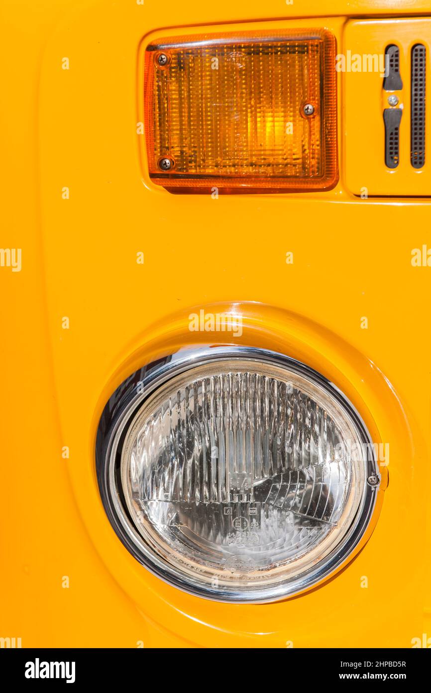 Esens, Germany - September 19, 2021: Frontal close-up view of the headlight and flashing light of an orange 1970's minibus at a vintage car meeting. Stock Photo