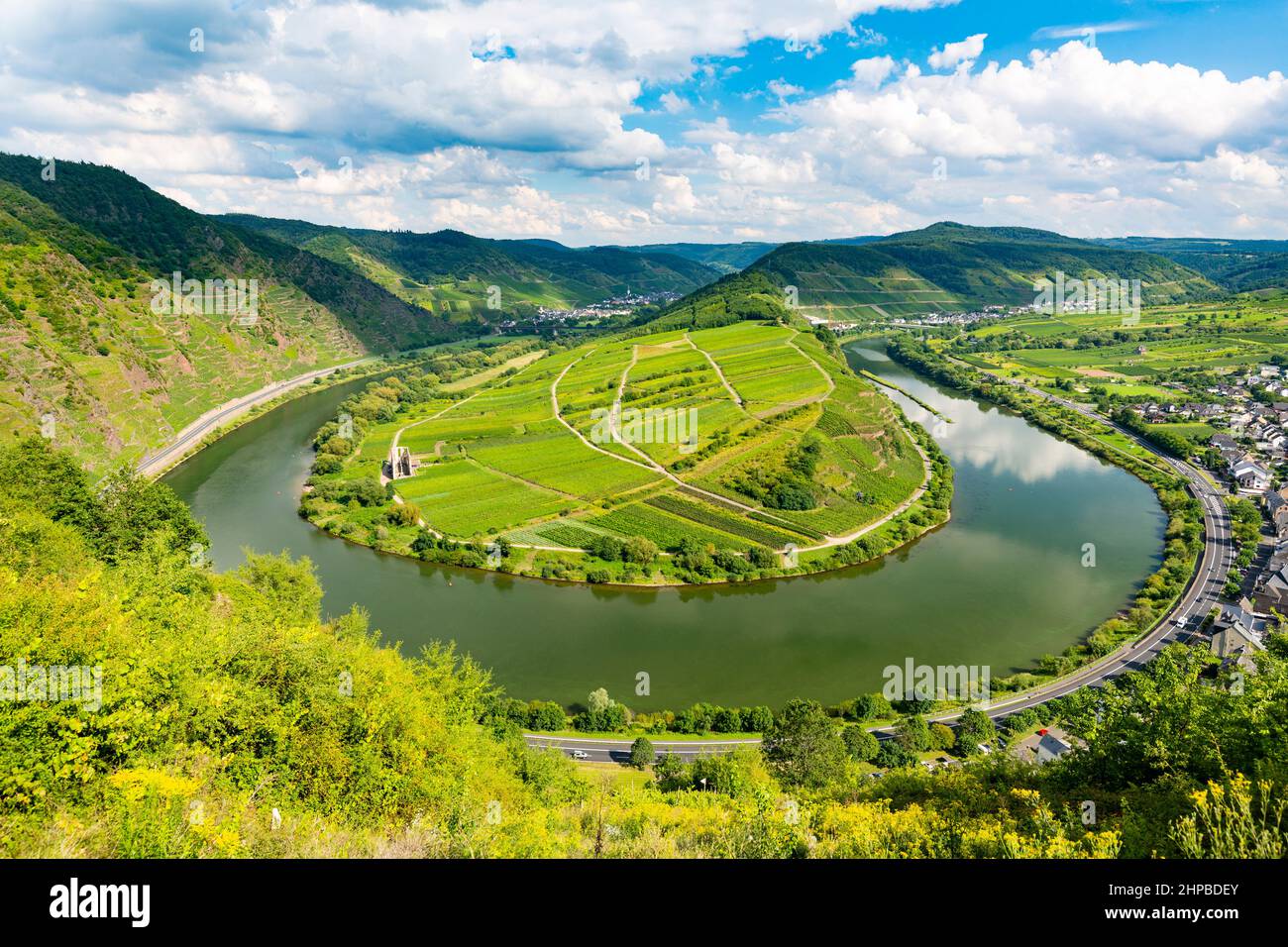 View of a riverbend of the Moselle River in the Eifel village of Bremm in Germany in summer. Seen from the Calmont vineyards with blue sky. Stock Photo