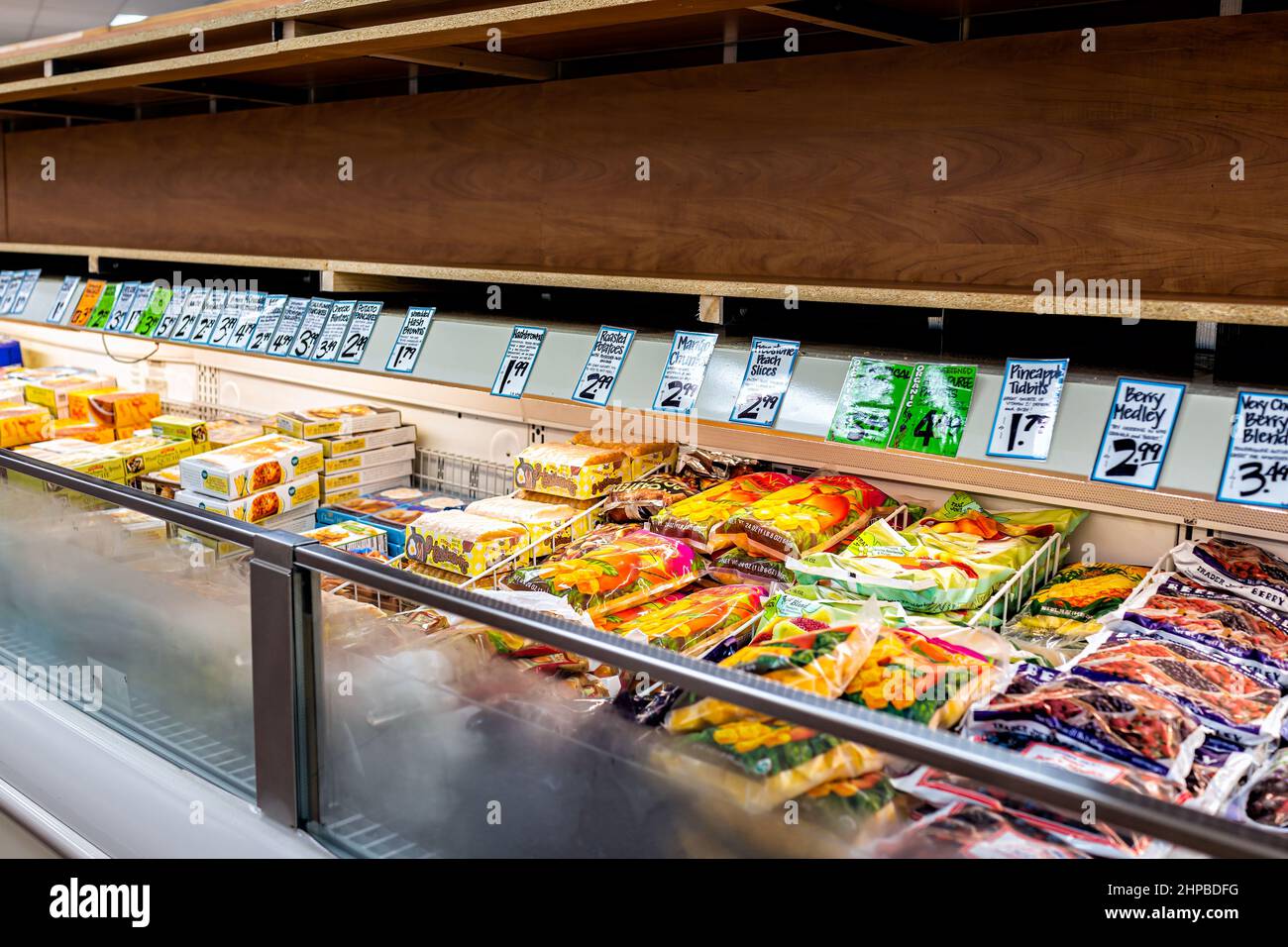 Reston, USA - July 9, 2020: Freezer shelf shelves at frozen aisle with price tags signs at Trader Joe's store during covid-19 with fruits, berries and Stock Photo