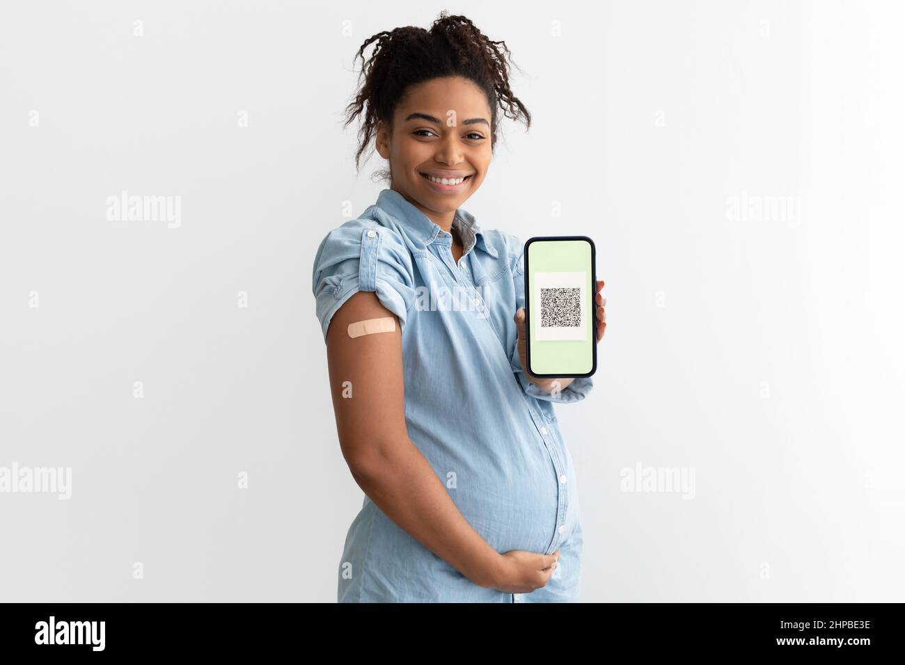 Pregnant black lady showing plaster on arm and digital certificate Stock Photo