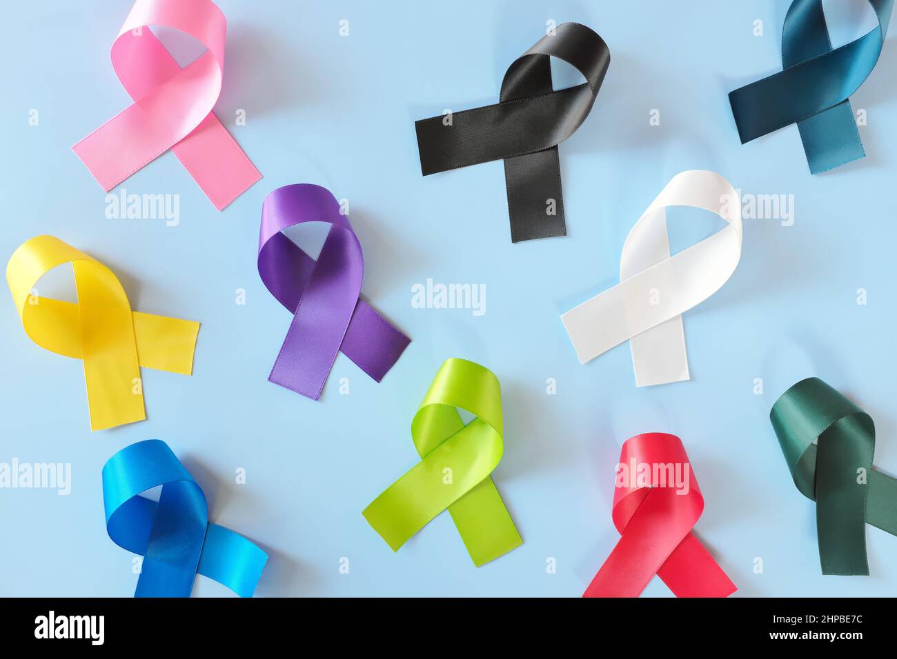 Set of colorful cancer awareness ribbons flat lay in blue background. World Cancer Day concept. Stock Photo