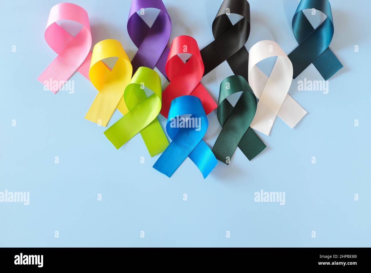 Set of colorful cancer awareness ribbons flat lay in blue background. World Cancer Day concept. Stock Photo