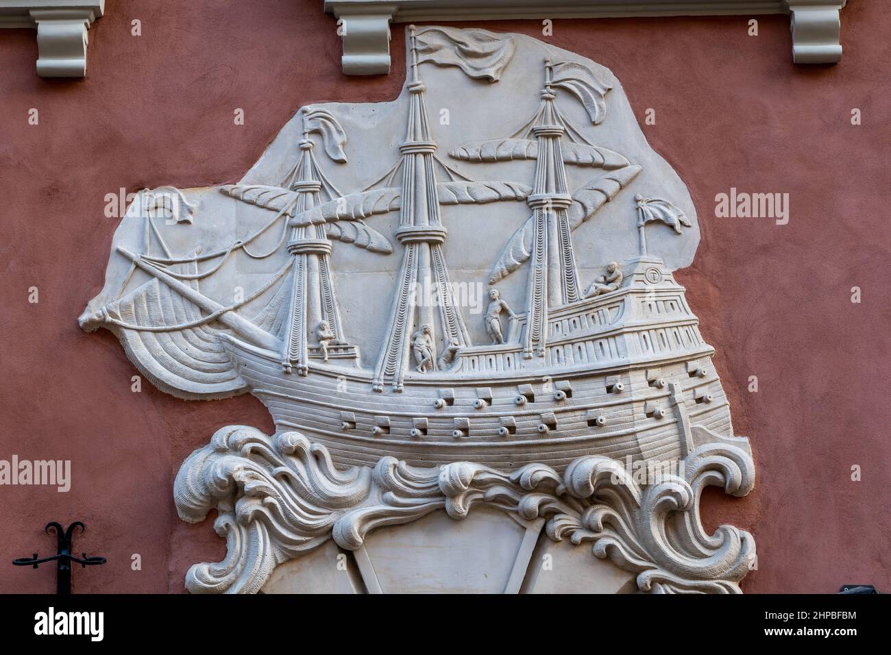 Relief of galleon sailing ship in waves on historic tenement house facade on Swietojanska street in the Old Town of Warsaw in Poland. Stock Photo